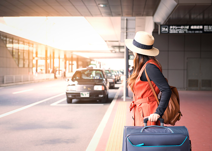 femme avec une valise attendant un taxi